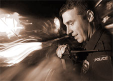 Officer on his radio in front of passing lights.