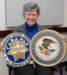Winnie Reed holding LEAA and DOJ shields.