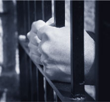 Hands holding the bars of a cell