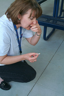 Photo of a woman bending down picking up a cigarette while holding her nose