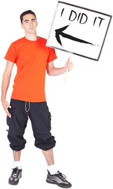 photo of a young man in 90's attire holding a sign that says "I Did It" with an arrow point at himself
