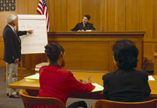 Photo inside a courtroom with a man pointing to a chart