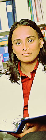 Woman in a lab coat in front of stacks of books